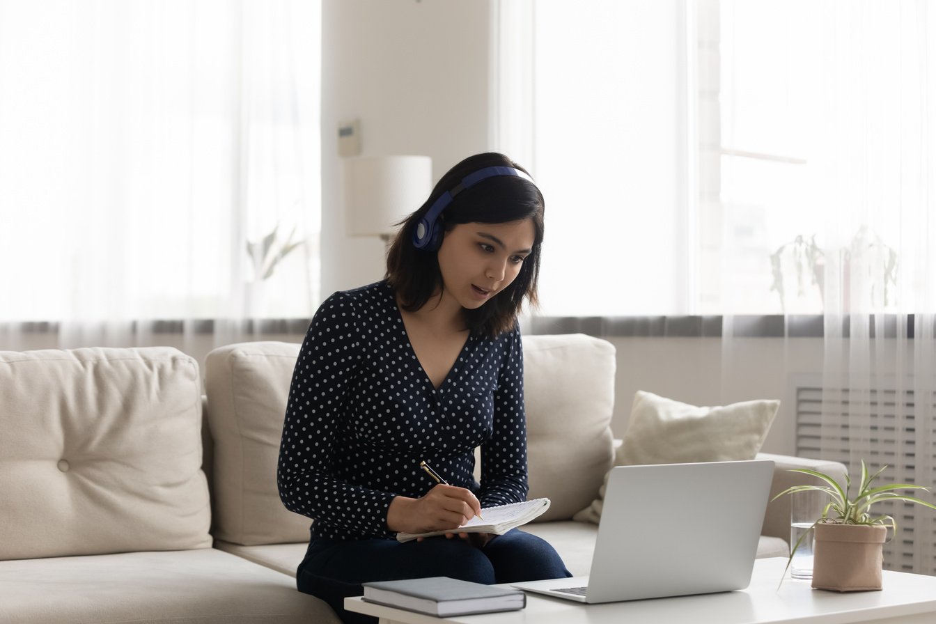 Concentrated asian lady employee participate in virtual meeting take records